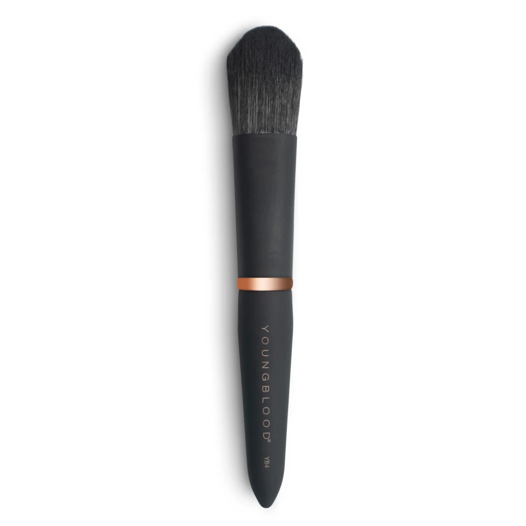 Close-up of a black makeup brush with dense bristles and a copper ferrule against a white background