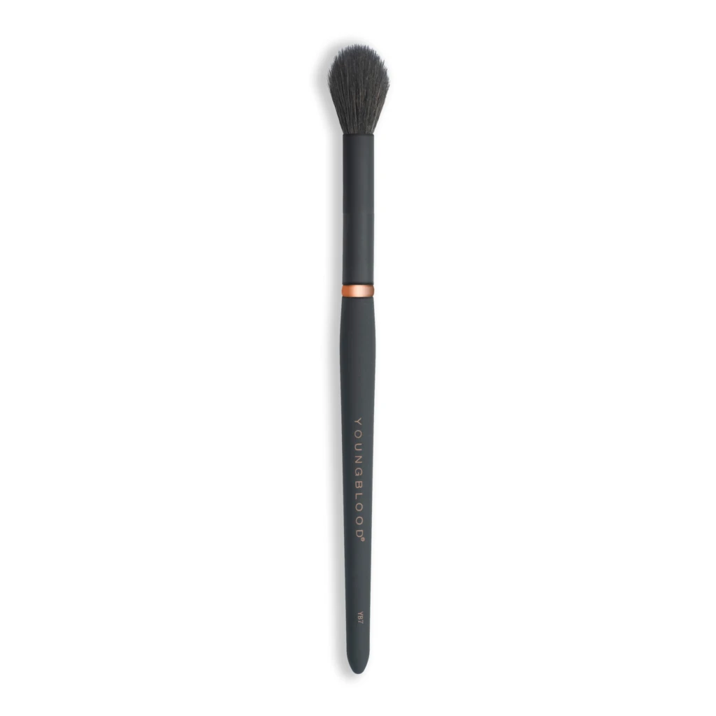 Full-length black makeup brush with dense dark bristles and a copper ring, viewed from above the bristles
