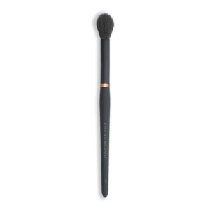 Full-length black makeup brush with dense dark bristles and a copper ring, viewed from above the bristles