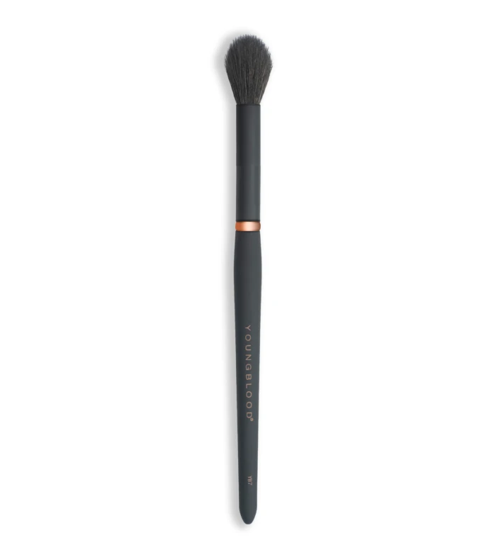 Full-length black makeup brush with dense dark bristles and a copper ring, viewed from above the bristles