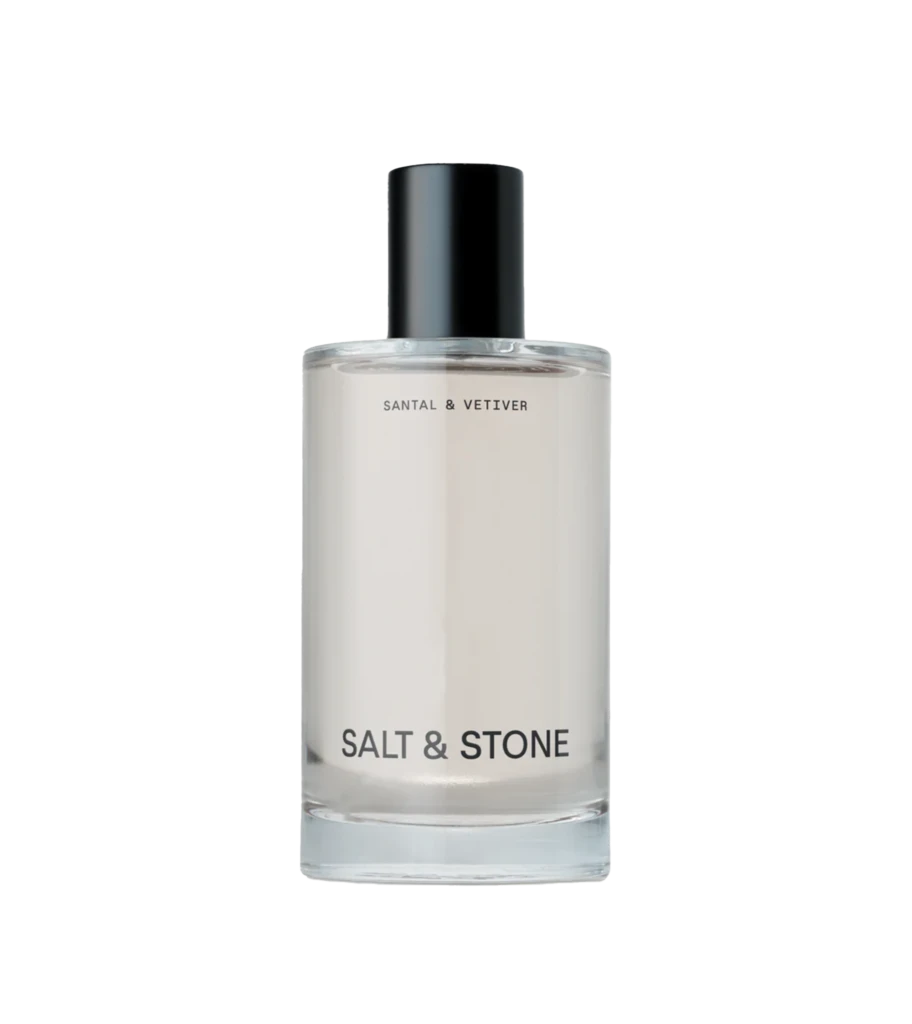 Clear glass bottle with a black cap and the label 'SALT & STONE' visible on a light background, product cosmetics bottle detail