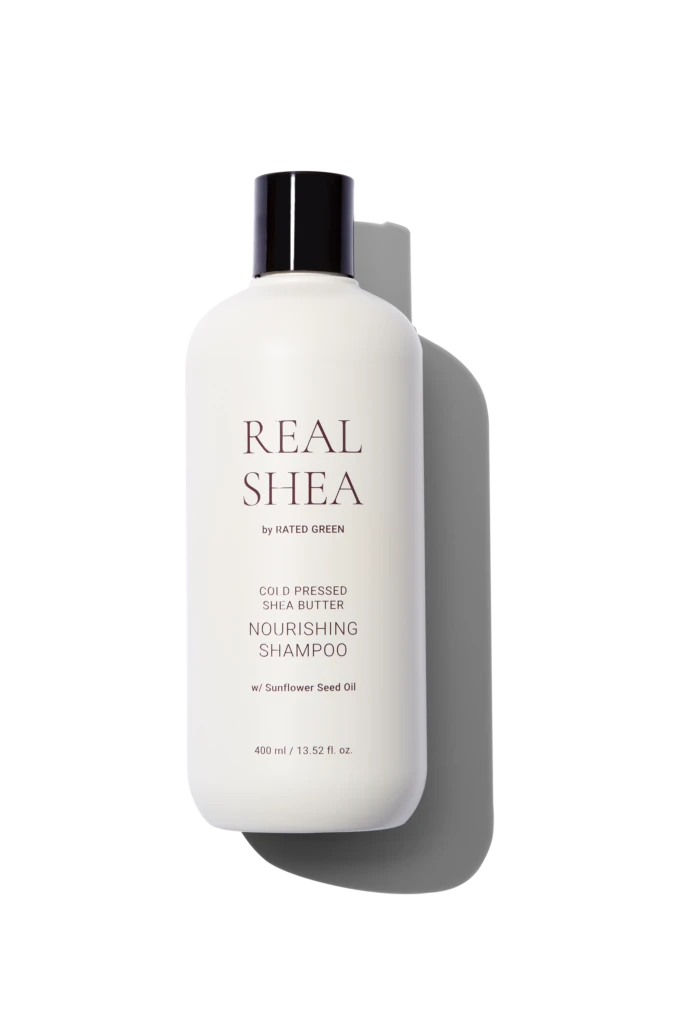 White shampoo bottle with a dark cap, labeled REAL SHEA by Rated Green, against a black background.