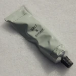 Pale green Bergamot & Eucalyptus hand cream tube resting on snowy surface with a dark cap visible at the bottom left corner, conveying winter skincare.