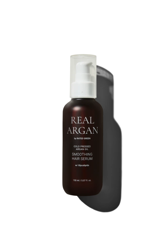Brown glass bottle with white pump labeled 'REAL ARGAN' containing smoothing hair serum, 150 ml, against a dark background.