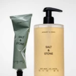 Two Bergamot & Hinoki Salt & Stone skincare bottles: a beige pump bottle and a green squeeze tube, shown side by side.