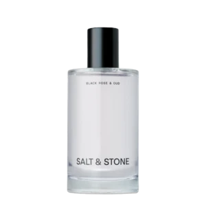 Perfume bottle with black cap and white label reading Black Rose & Oud, Salt & Stone visible at base.