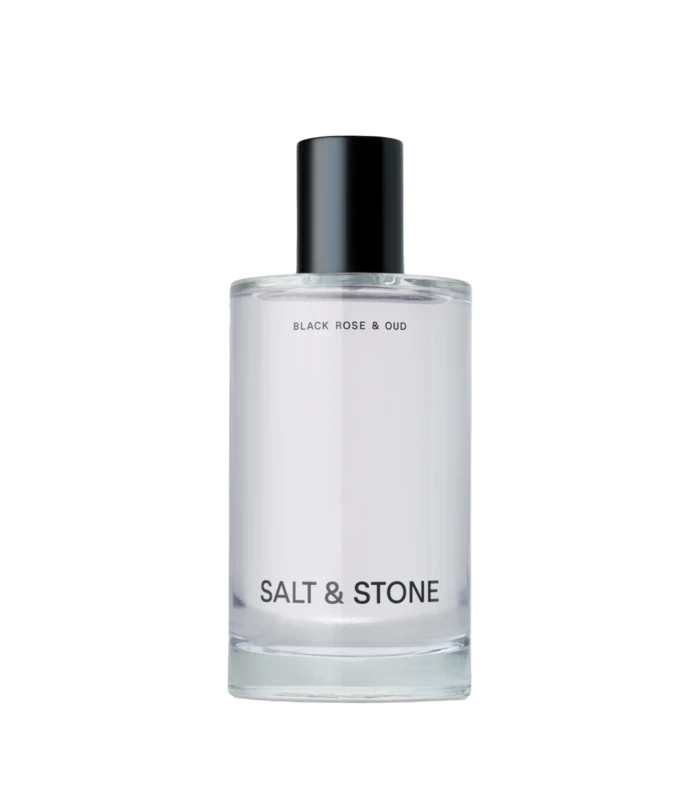 Perfume bottle with black cap and white label reading Black Rose & Oud, Salt & Stone visible at base.