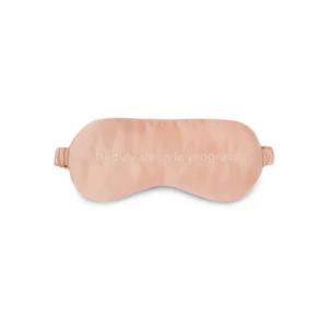 Pink satin sleep mask with adjustable straps and embroidered slogan 'beauty sleep in progress'.