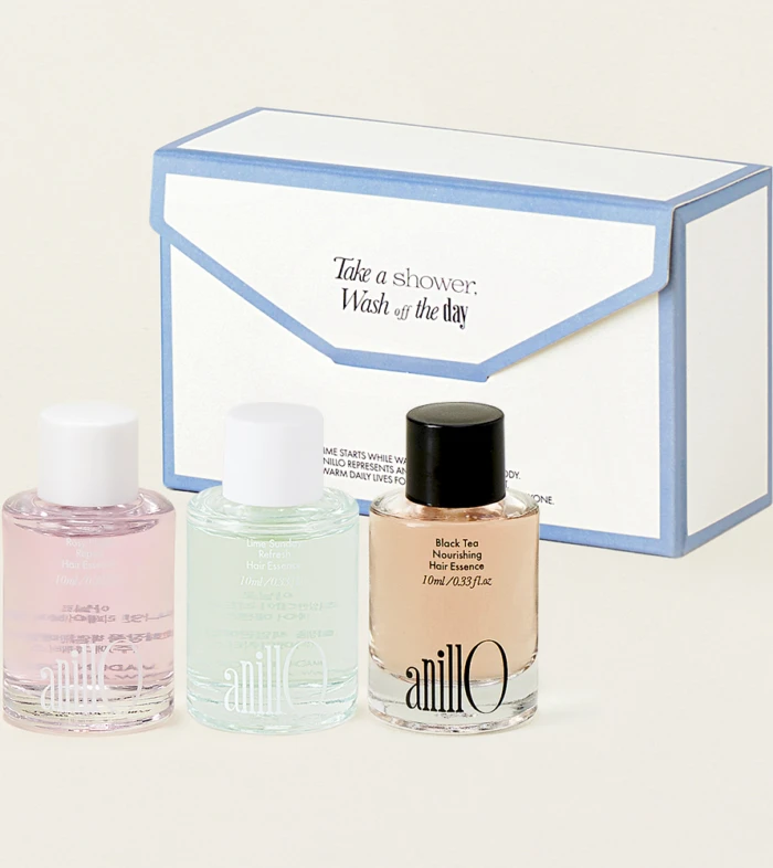 Three pastel nail polish bottles (pink, mint, nude) sit in front of a white and blue boxed set with an envelope design, suggesting a gift set.