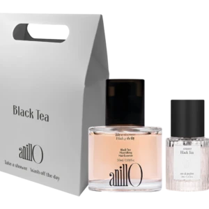 Tall white packaging box with a built-in handle reading 'Black Tea' beside a pink perfume bottle and a clear glass bottle on a dark background; product set.