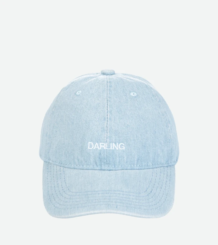 Close-up of a light blue denim cap from above, showing the top button and stitched panels with the word 'DARLING' on the back.