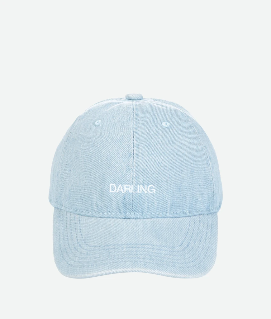 Close-up of a light blue denim cap from above, showing the top button and stitched panels with the word 'DARLING' on the back.