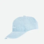 Close-up of a light-blue denim baseball cap cropped against a pale background, showing the top and brim edge.
