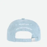 Back view of a light blue denim cap with an adjustable strap and white embroidered text on the back panel.