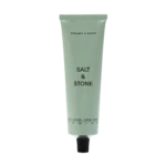 Pale green Bergamot & Hinoki body lotion tube with a black cap on a black background, upright and centered.