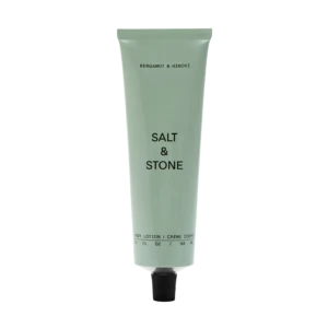 Pale green Bergamot & Hinoki body lotion tube with a black cap on a black background, upright and centered.