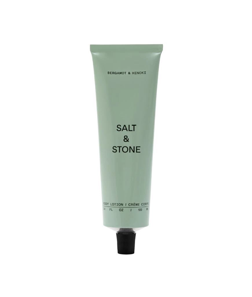 Pale green Bergamot & Hinoki body lotion tube with a black cap on a black background, upright and centered.