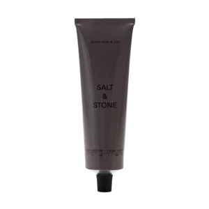 Vertical gray lotion tube labeled 'BLACK ROSE & OUD' with a black ribbed cap, set against a black background.