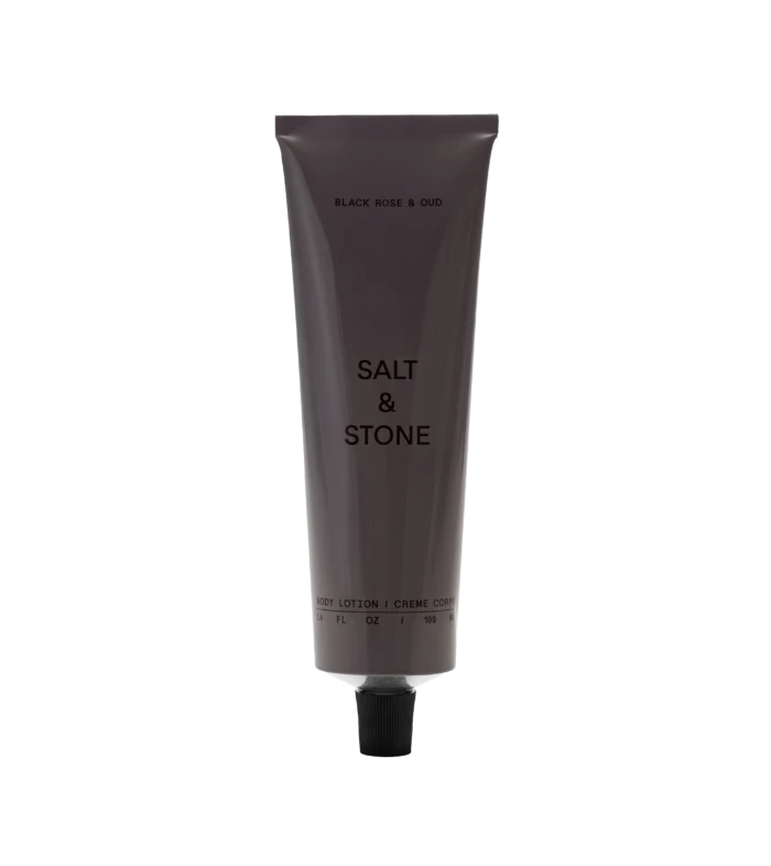 Vertical gray lotion tube labeled 'BLACK ROSE & OUD' with a black ribbed cap, set against a black background.