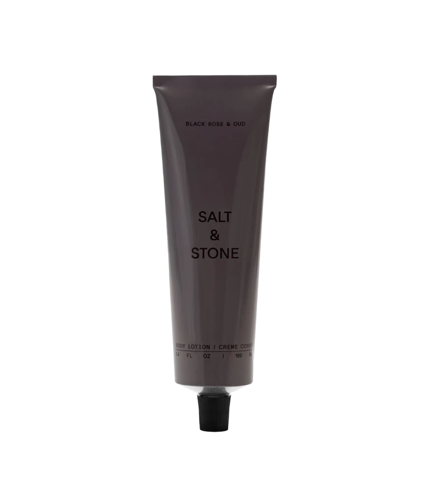 Vertical gray lotion tube labeled 'BLACK ROSE & OUD' with a black ribbed cap, set against a black background.