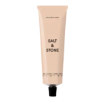 Pale pink body lotion tube standing upright; reads 'Salt & Stone' with 'Saffron & Cedar' scent on a black background.