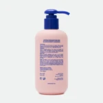 Pink lotion/body wash bottle with a blue pump dispenser on a light background, product label visible on the front.