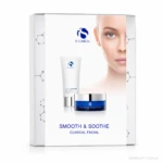 Boxed iS Clinical skincare set (Smooth & Soothe Clinical Facial) with a white tube and blue jar in front of a partial model's face on a white background.
