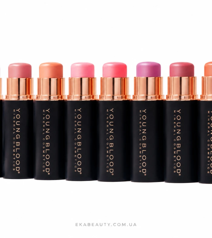 Row of black lipstick tubes with rose-gold caps in a line, showing pink to coral lipstick shades on a white background.