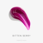 Glossy purple lipstick swatch curved across a white background, with the text 'BITTEN BERRY' beneath.