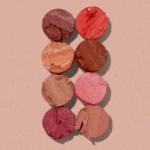 Crushed blush powders in pink and red tones, arranged in a vertical column on a peach background.