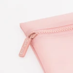 Close-up of a pale pink zippered pouch with visible stitching along the edge.