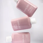 Four pink sunscreen lotion bottles labeled Darling, SPF 30, arranged diagonally on a white surface with white caps visible.