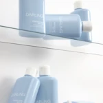Blue sunscreen bottles with white caps labeled 'DARLING' on a white background, grouped together on a shelf.