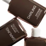 Close-up of brown glass bottles with white caps, labeled SOOTHE-ME Face and Body After Sun Lotion.
