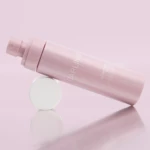 Pink sunscreen spray bottle angled diagonally on a pale pink background.