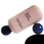 Close-up of a pink lotion bottle tilted diagonally with round dark capsules around it on a white background.