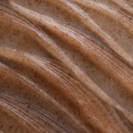 Close-up of raw meat covered with transparent plastic wrap, speckled with red spices.