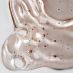 Macro shot of pale pink glossy liquid with numerous bubbles and flowing folds.