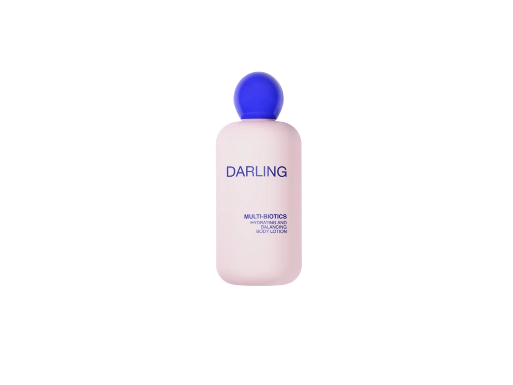 Pink bottle of Darling Multi-Biotics hydrating and balancing body lotion with a blue cap against a black background