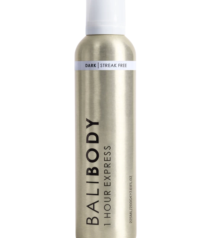 A tall cylindrical metallic spray bottle with a white cap and a light band around the neck reading 'DARK | STREAK FREE'