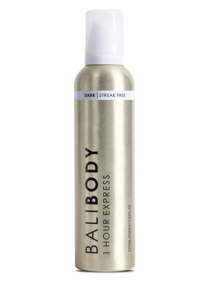 A tall cylindrical metallic spray bottle with a white cap and a light band around the neck reading 'DARK | STREAK FREE'