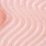 Close-up of pale pink frosting with wavy ridges and small specks for texture.
