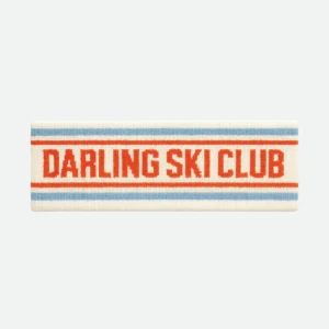 Knitted headband in cream with blue and red stripes, text reads ‘DARLING SKI CLUB’ in red.