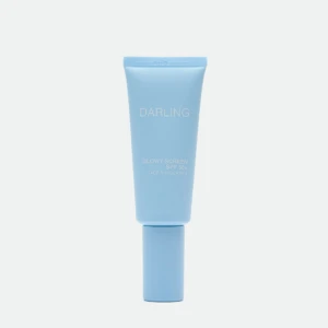 Blue sunscreen tube labeled 'DARLING' with SPF 50+ standing upright against a pale background, showing 'GLOWY SCREEN' text.