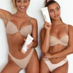Two women in beige lingerie pose against a white backdrop, holding Balibody tubes showing product branding.