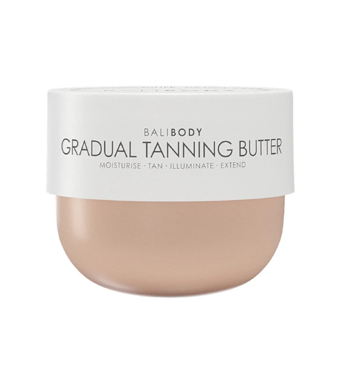 Close-up of a white cosmetic jar displaying the text 'BALI BODY GRADUAL TANNING BUTTER' with beige lotion visible at the bottom edge, indicating a tanning product.