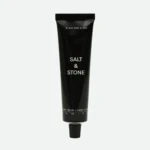 Tall black Salt & Stone hand cream tube with white text, photographed vertically.