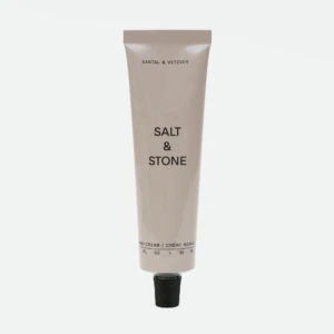 Beige Salt & Stone hand cream tube standing upright with a black cap at the bottom and visible brand text on the front.