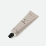 Beige Salt & Stone skincare tube with black cap, laid diagonally on a white background