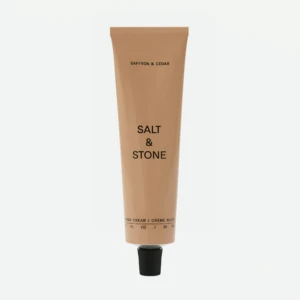 Beige squeeze tube of skincare labeled 'Saffron & Cedar' with 'Salt & Stone' brand, standing upright.